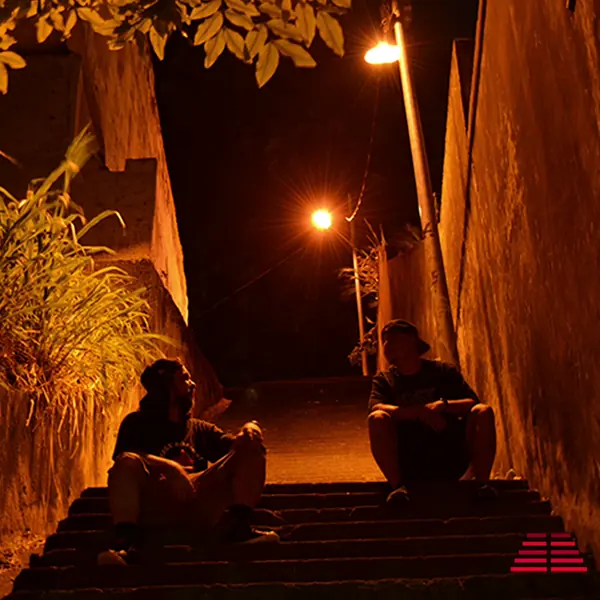Capa do EP Um Degrau Por Vez Vol.1: dois integrantes do 1DV sentados numa escadaria estreita à noite, iluminada por postes de luz laranja